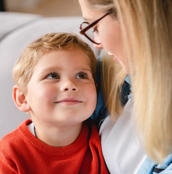 A smiling boy looking up at his mom