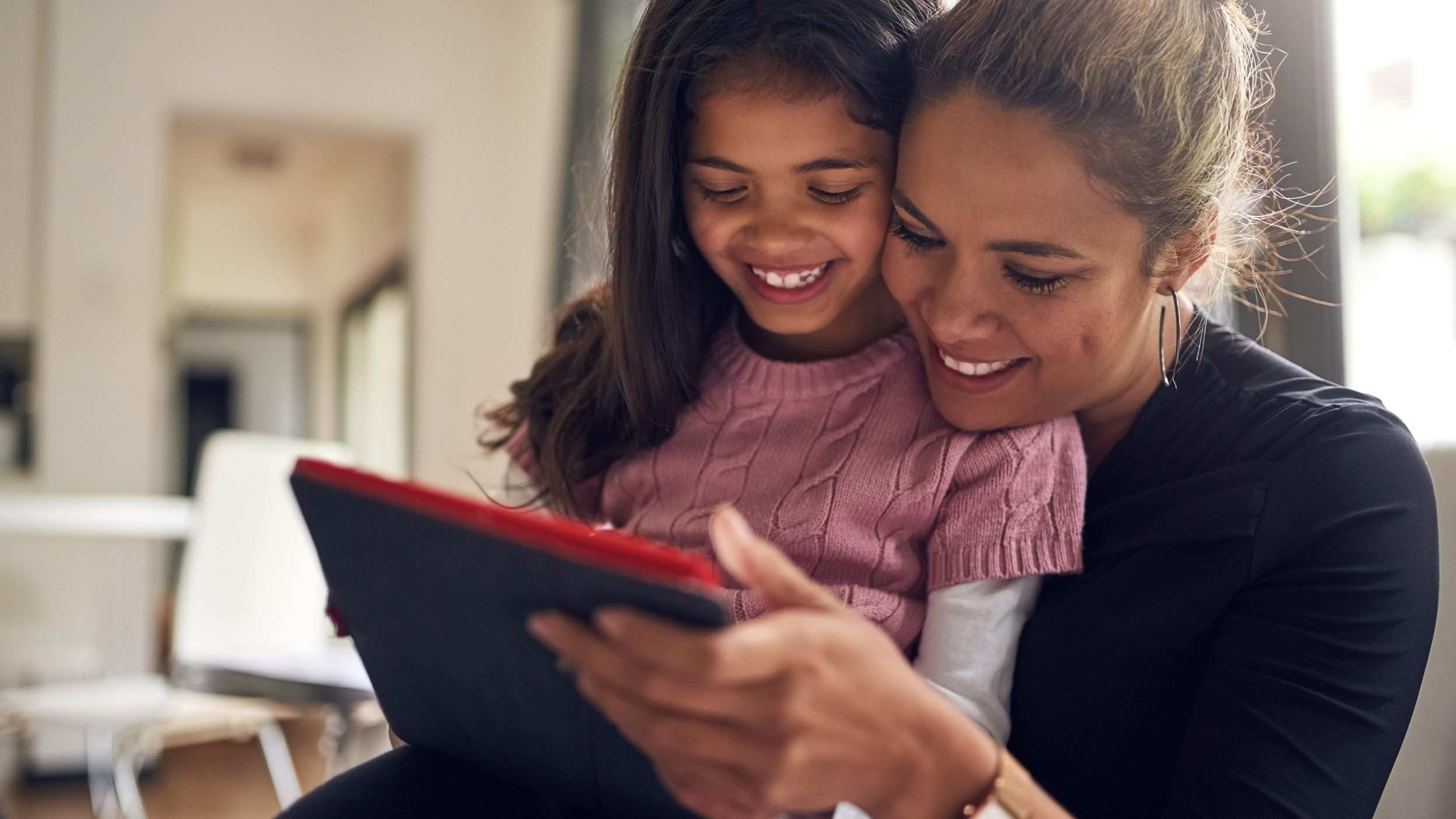 Mom and daughter smiling at content on a tablet device