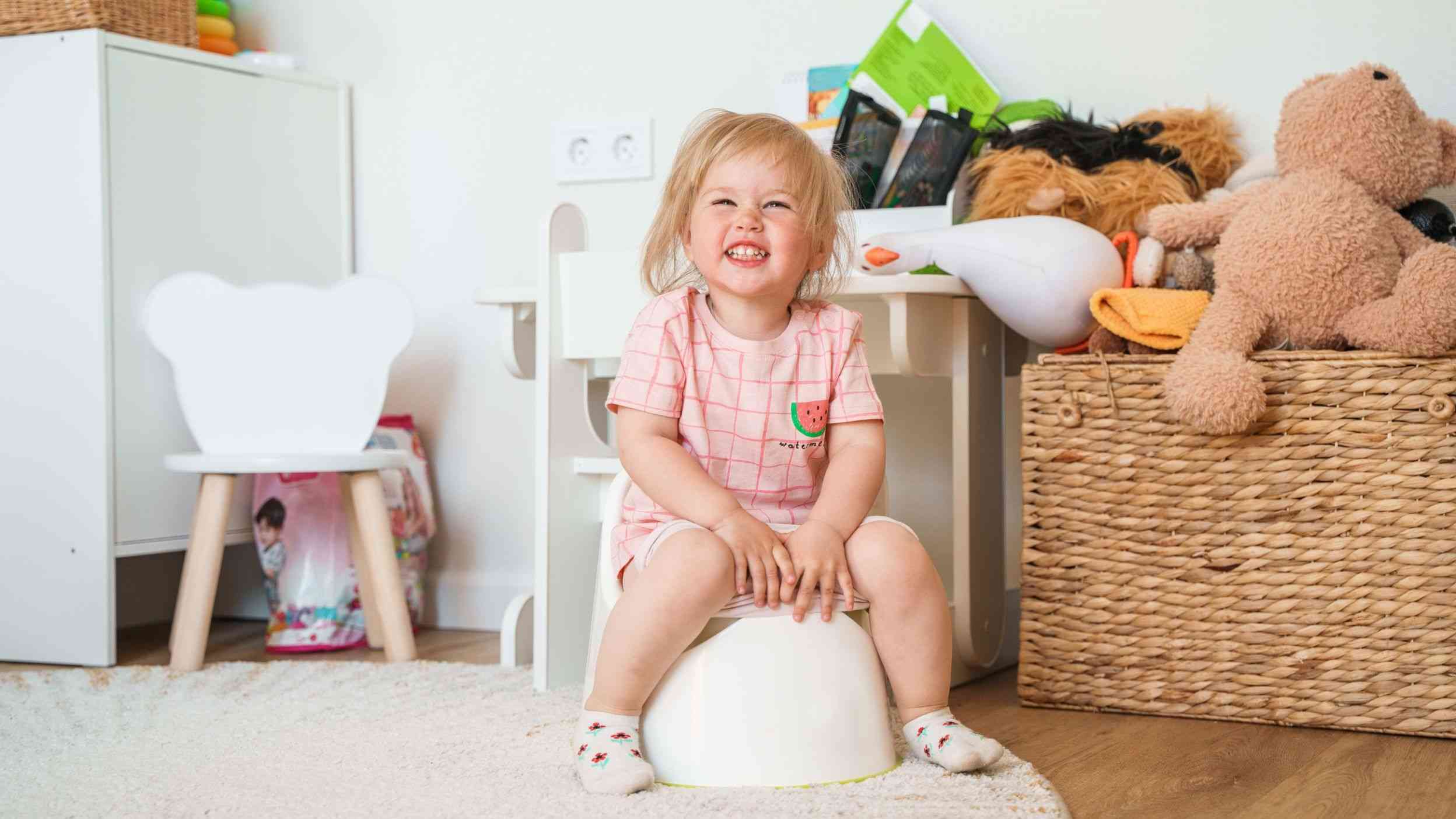 A toddler sitting on a potty and scrunching up her nose
