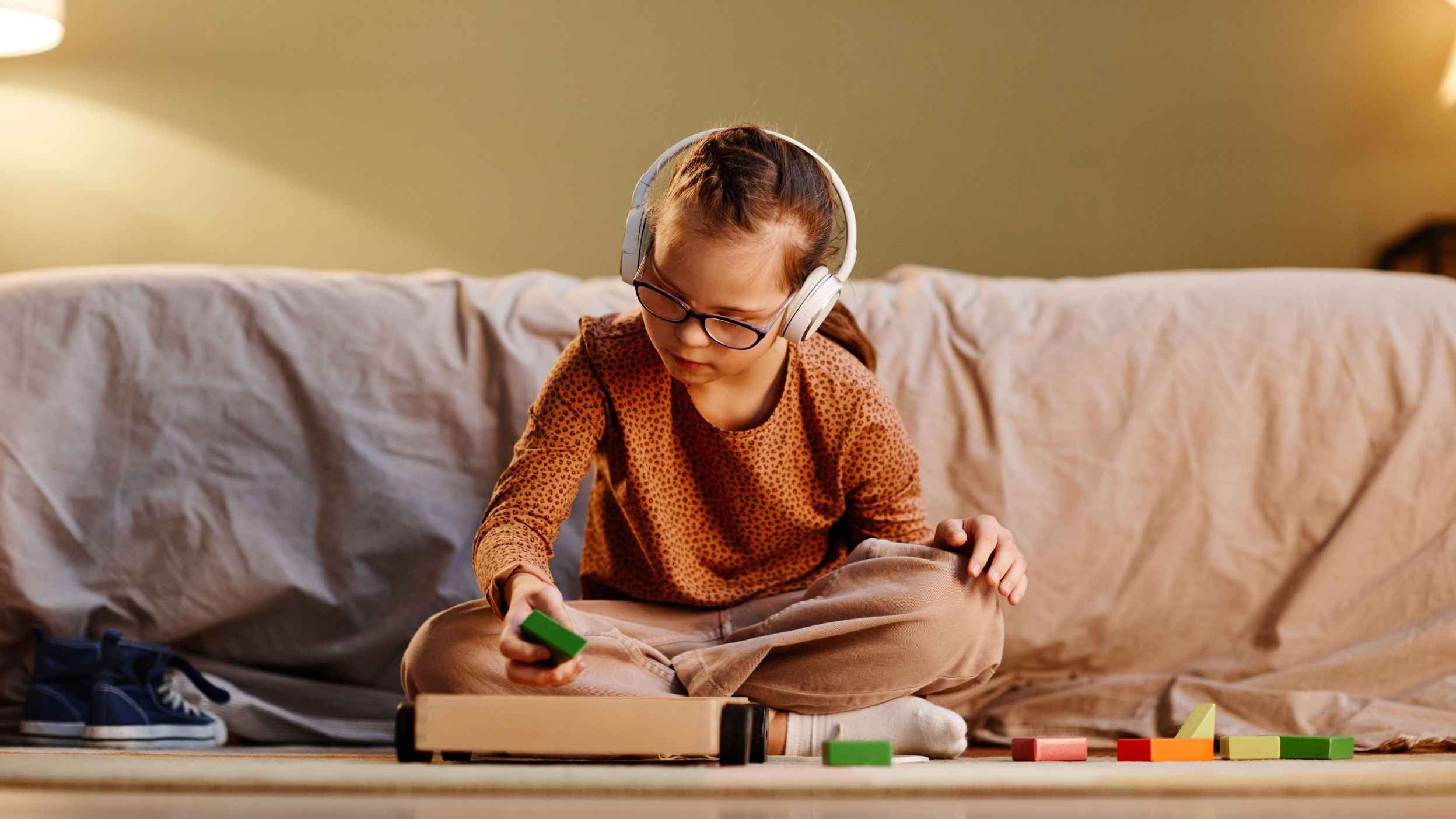 A girl with glasses and earphones playing with blocks