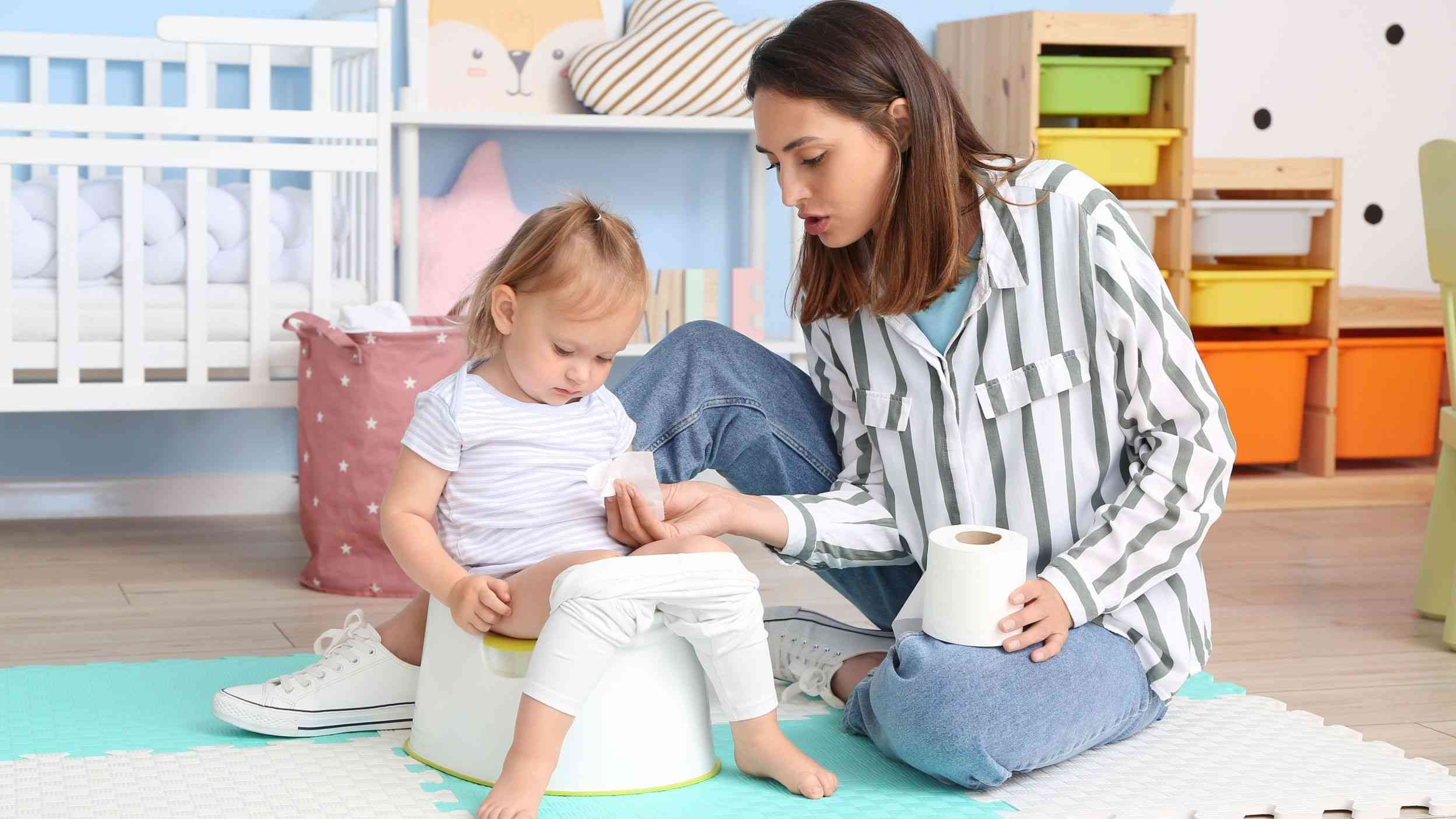 A mom sitting next to her toddler sitting on a potty