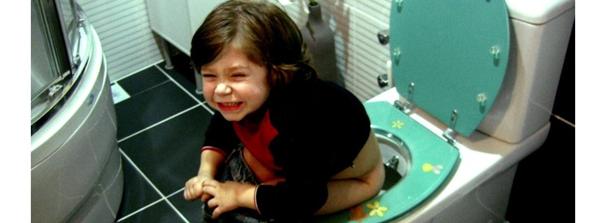 A toddler sitting on the toilet and bearing down